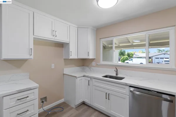 a kitchen with granite countertop white cabinets and a window