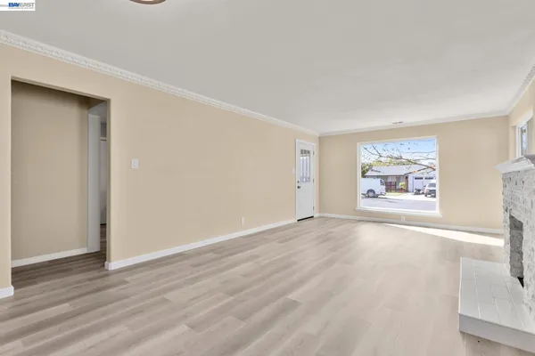 a view of an empty room with wooden floor and window