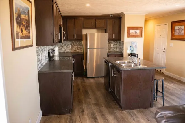 a kitchen with stainless steel appliances a refrigerator a sink a stove a table and chairs