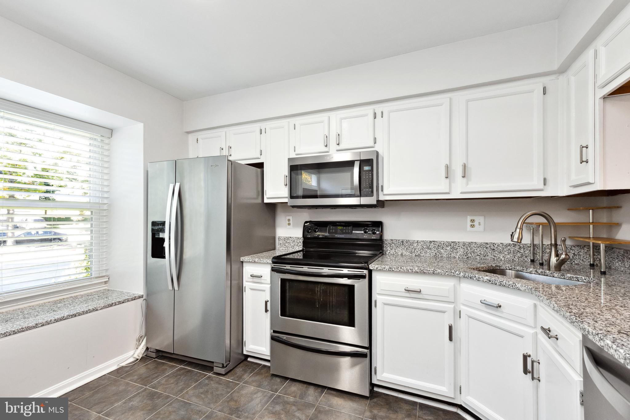9525 Clocktower Lane Columbia, MD 21046 - Photo 4 of 19 a kitchen with granite countertop white cabinets stainless steel appliances and a window