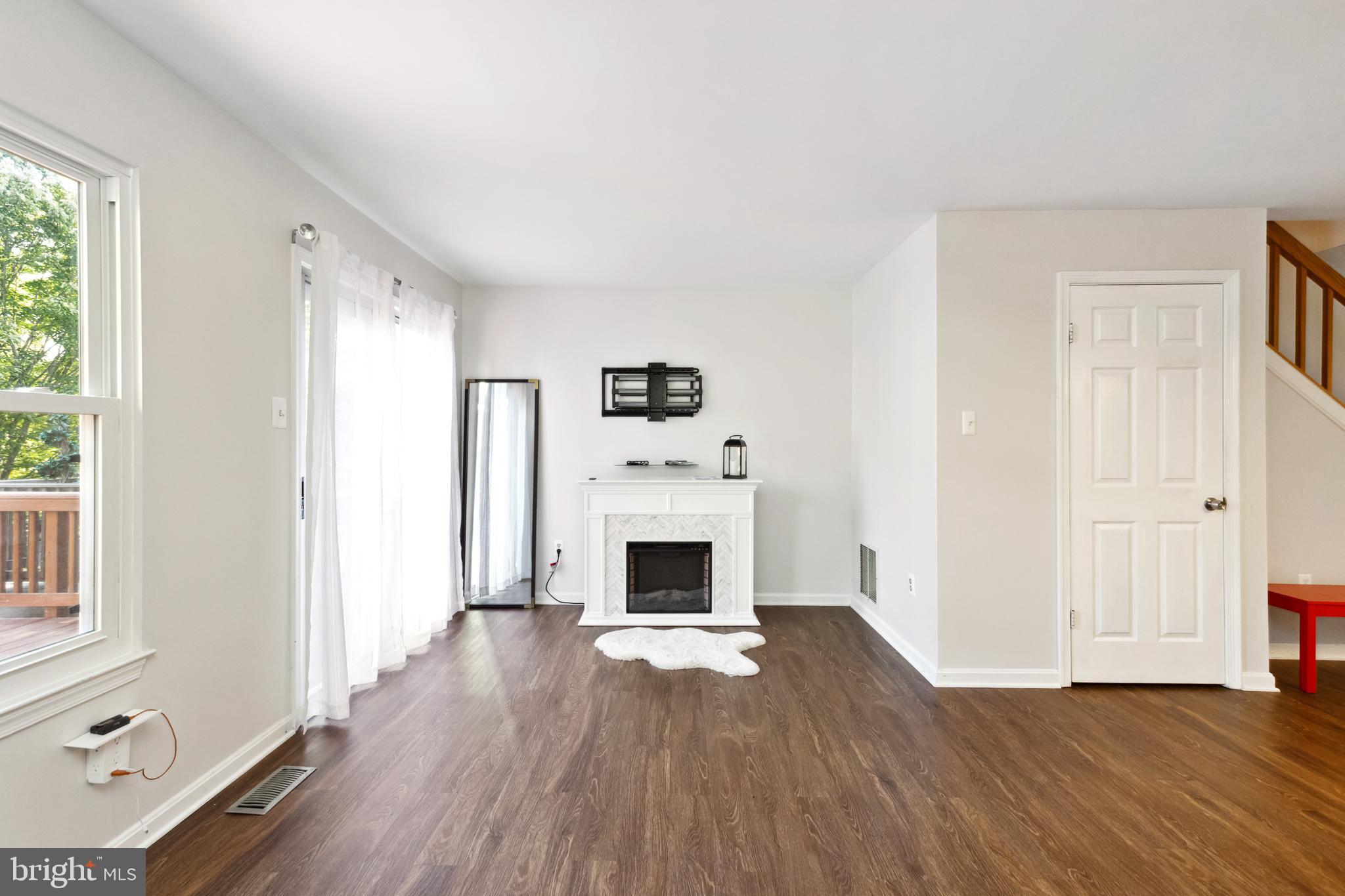 9525 Clocktower Lane Columbia, MD 21046 - Photo 8 of 19 an empty room with windows fireplace and wooden floor