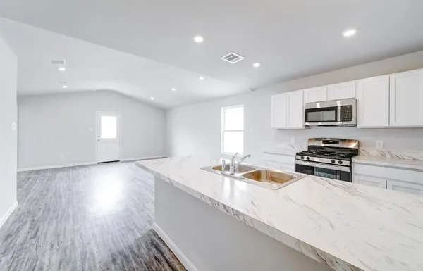 a kitchen with stainless steel appliances granite countertop a sink dishwasher stove and microwave with wooden floor