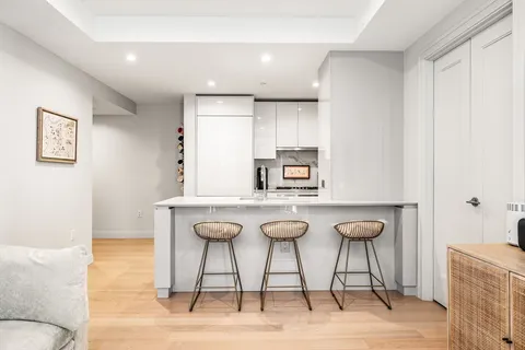 a kitchen with stainless steel appliances kitchen island a chandelier a sink and chairs