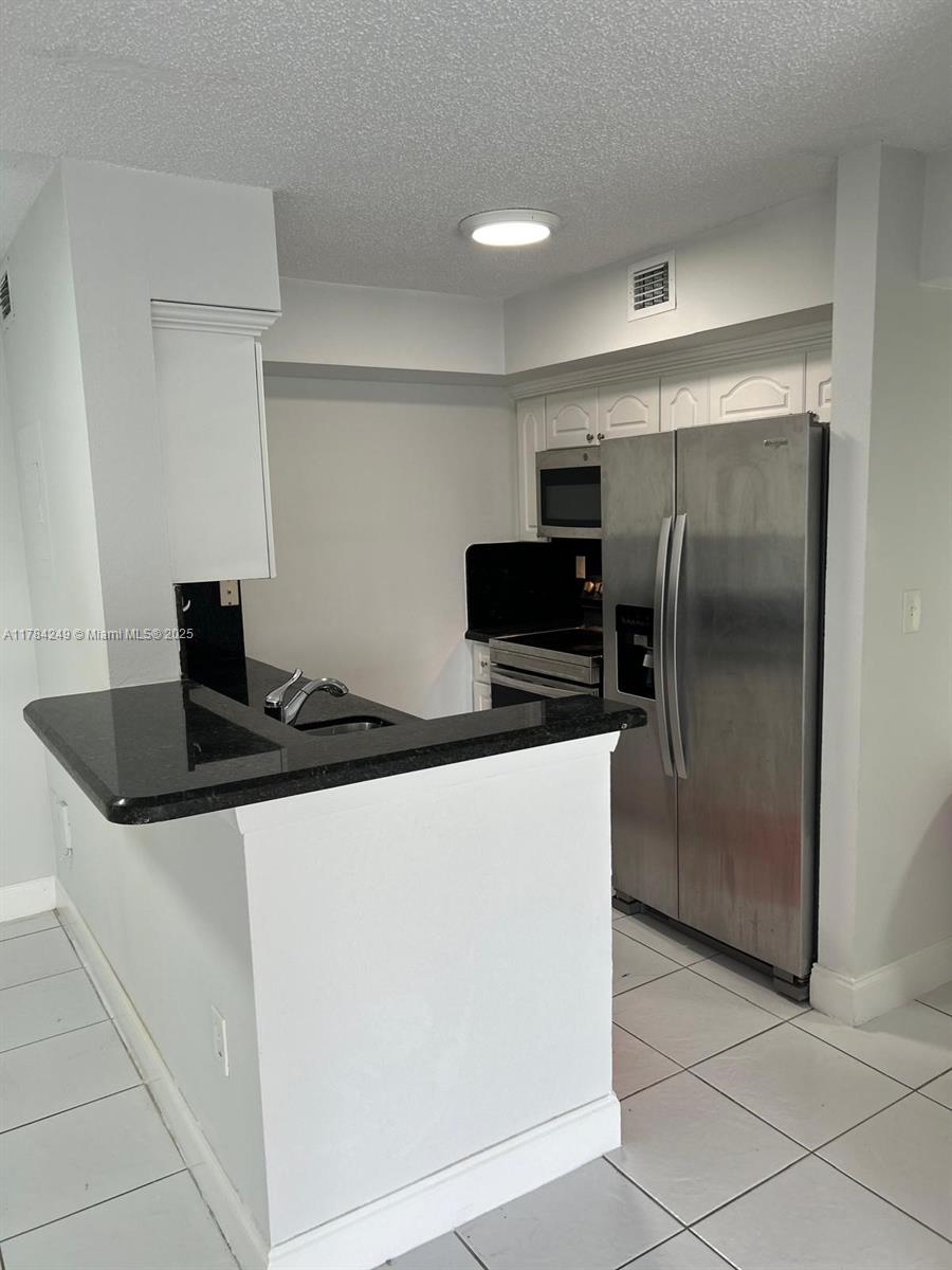 15201 Southwest 80th Street, Unit 302 Miami, FL 33193 - Photo 7 of 30 a kitchen with granite countertop a refrigerator and a stove top oven