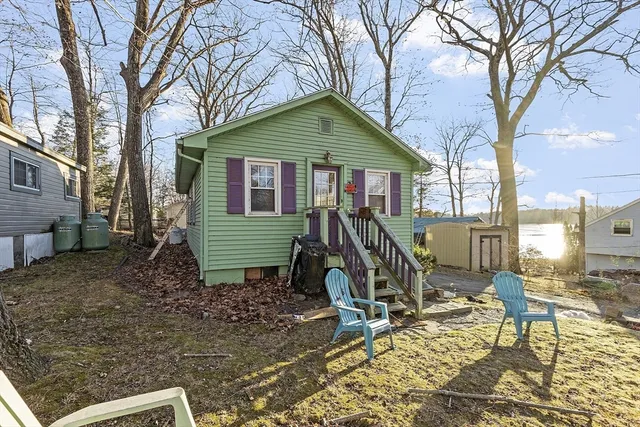 a view of a house with a yard chairs and wooden fence
