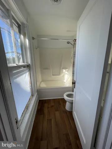a bathroom with a granite countertop toilet a sink a mirror and a shower
