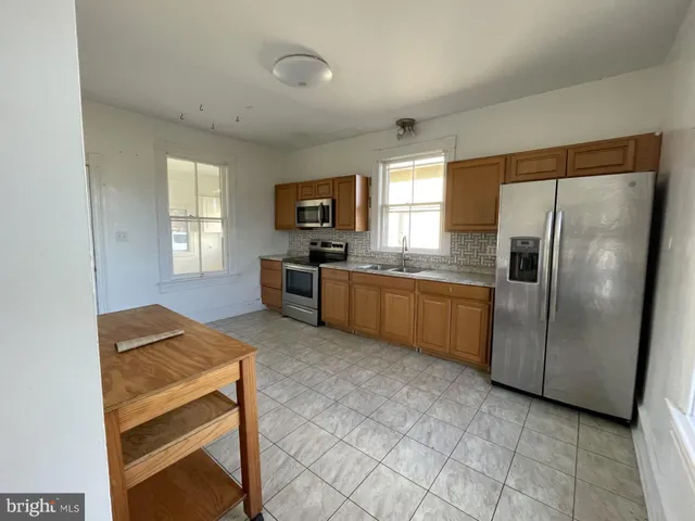 a kitchen with granite countertop a refrigerator stove top oven and sink