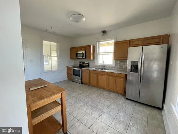 a kitchen with granite countertop a refrigerator stove top oven and sink