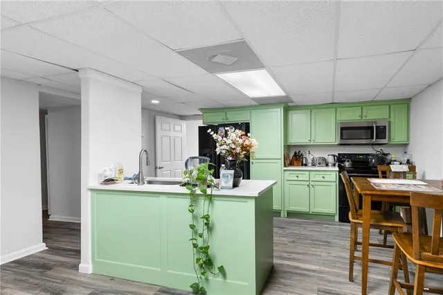 a room with kitchen island stainless steel appliances a sink cabinets and wooden floor