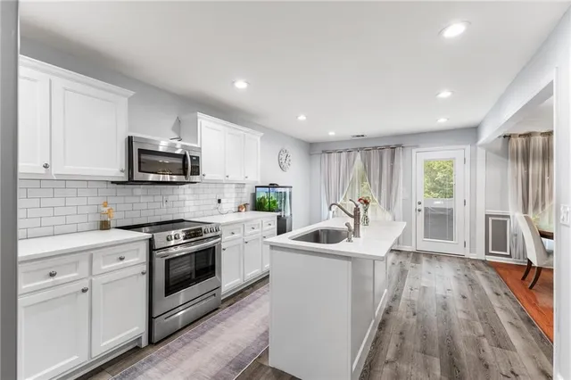 a kitchen with stainless steel appliances a sink a stove a refrigerator cabinets and a center island