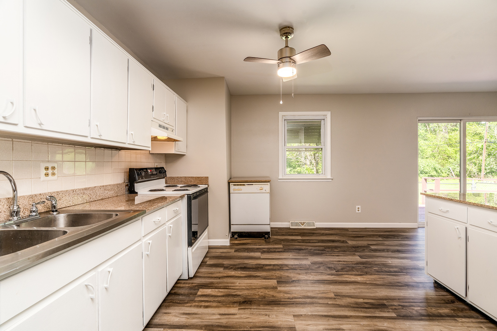 1307 North 16th Street Murphysboro, IL 62966 - Photo 6 of 27 a kitchen with granite countertop a stove a sink and white cabinets with wooden floor