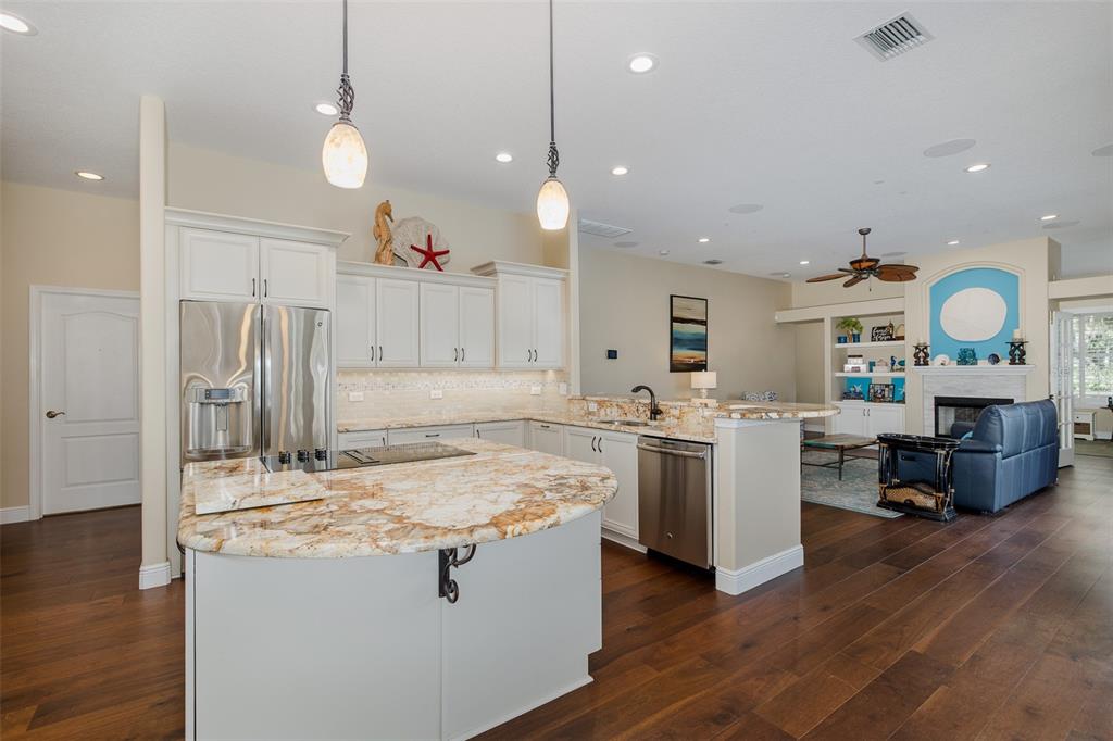 2928 Waters Edge Road Palm Harbor, FL 34685 - Photo 18 of 52 a large kitchen with kitchen island a stove a sink a refrigerator and a dining table with wooden floor