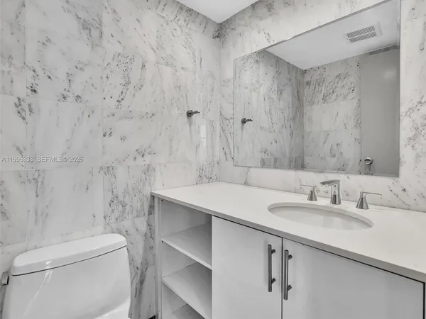 a bathroom with a granite countertop sink mirror and cabinets