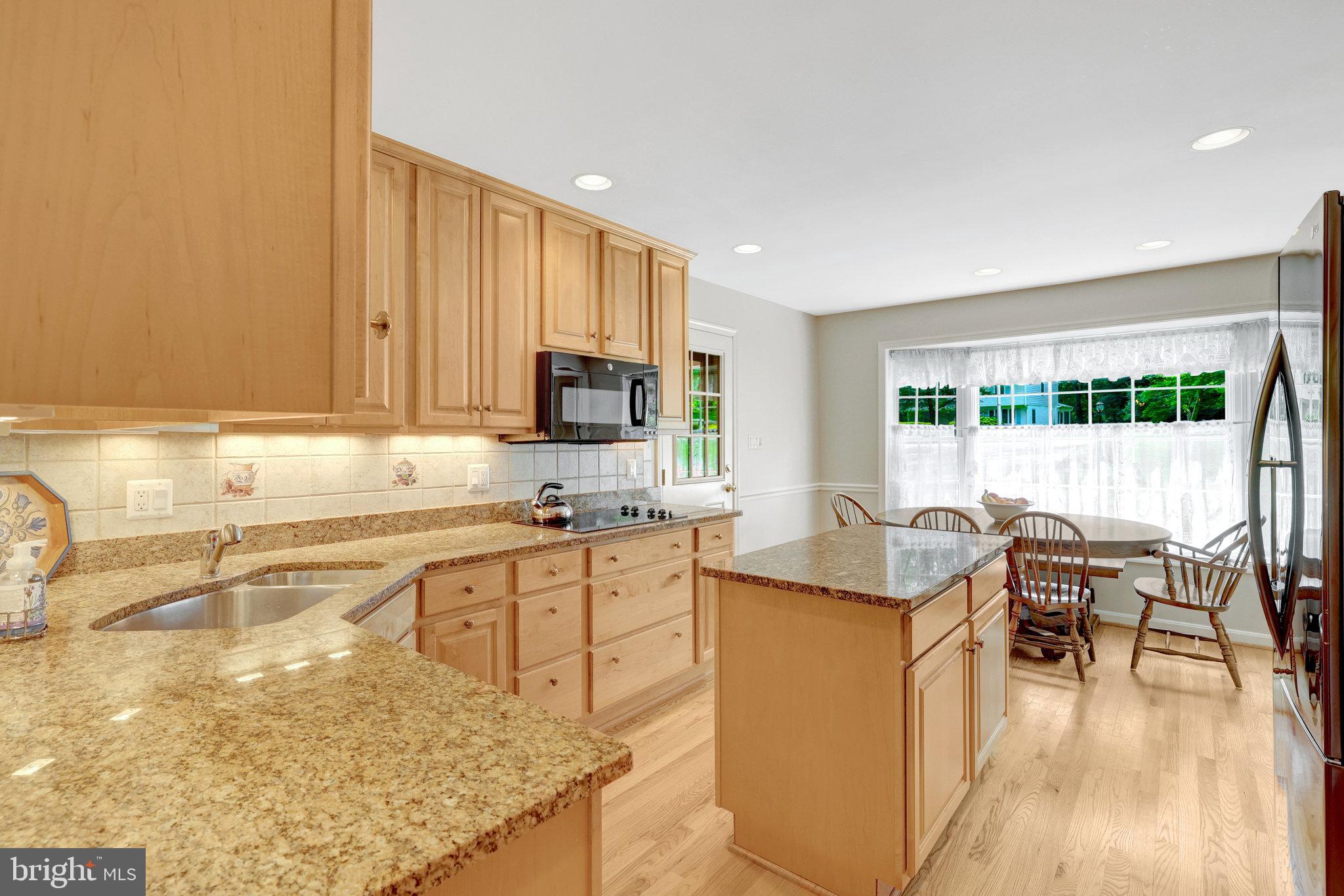 2042 Carrhill Road Vienna, VA 22181 - Photo 17 of 80 a kitchen with stainless steel appliances granite countertop a stove top oven a sink a dining table and chairs with wooden floor