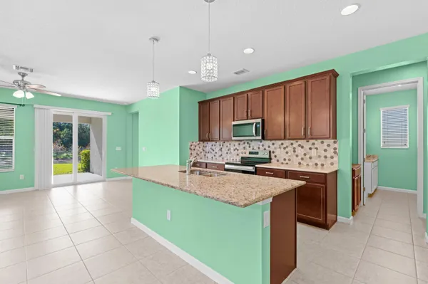 a large kitchen with kitchen island granite countertop a sink and a stove top oven