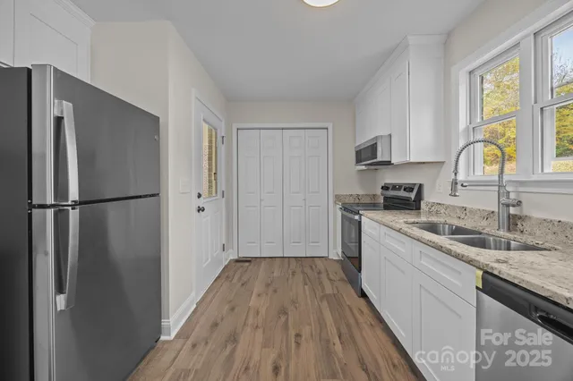 a kitchen with a sink a refrigerator a window and cabinets