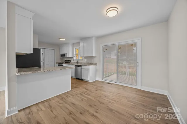 a large kitchen with wooden floor and stainless steel appliances