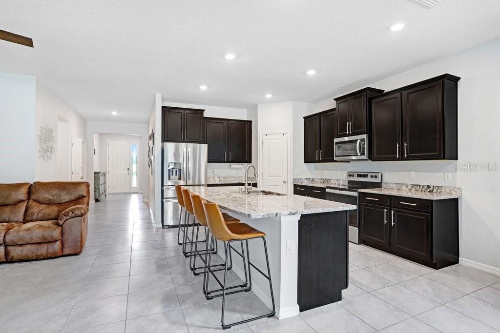 16619 Goose Ribbon Place Wimauma, FL 33598 - Photo 11 of 38 a kitchen with stainless steel appliances granite countertop a stove a sink a refrigerator and a microwave