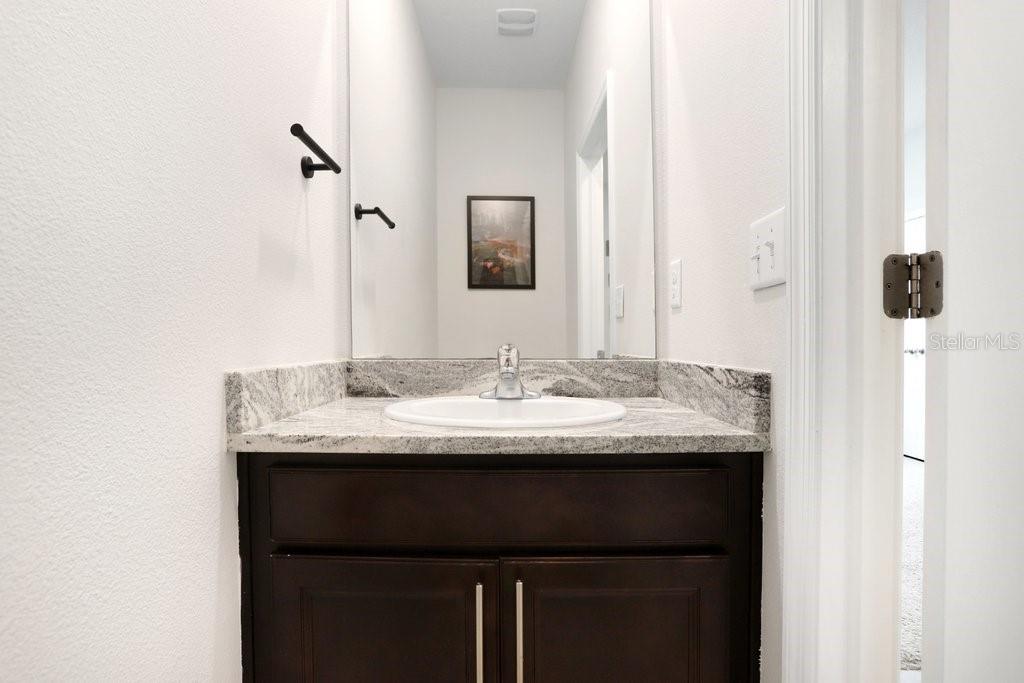 16619 Goose Ribbon Place Wimauma, FL 33598 - Photo 24 of 38 a bathroom with a granite countertop sink and a mirror