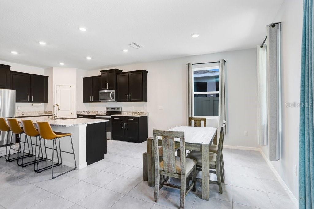16619 Goose Ribbon Place Wimauma, FL 33598 - Photo 8 of 38 a kitchen with stainless steel appliances kitchen island granite countertop a sink and cabinets