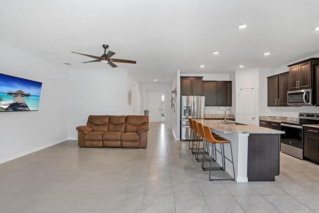 16619 Goose Ribbon Place Wimauma, FL 33598 - Photo 10 of 38 a living room with stainless steel appliances furniture a flat screen tv and kitchen view