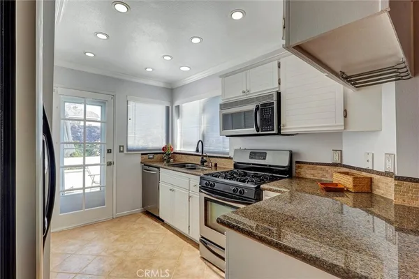a kitchen with stainless steel appliances granite countertop a stove a sink and a microwave