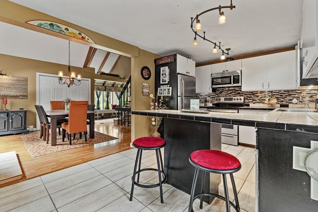 33 R F Higgins Drive Norwell, MA 02061 - Photo 8 of 34 a kitchen with stainless steel appliances kitchen island granite countertop a dining table chairs and sink