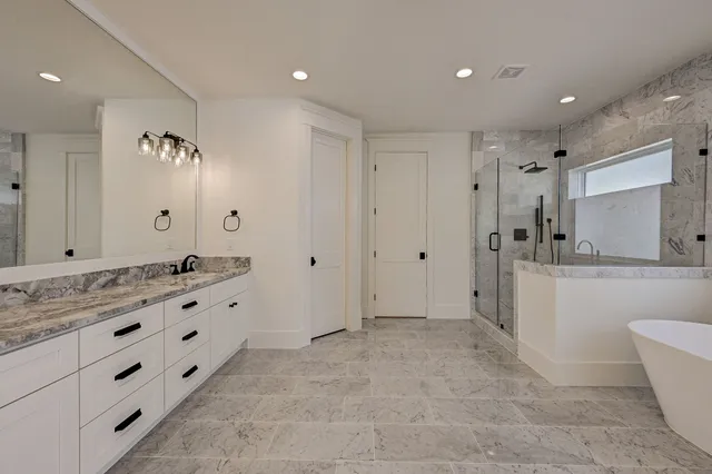 a bathroom with a granite countertop sink a toilet a large mirror and shower