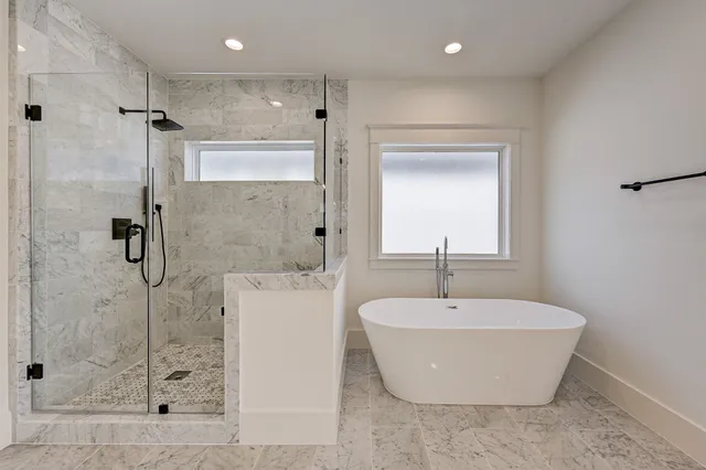 a bathroom with a white bath tub a shower and mirror