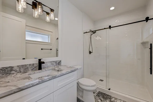 a bathroom with a granite countertop sink a toilet and shower
