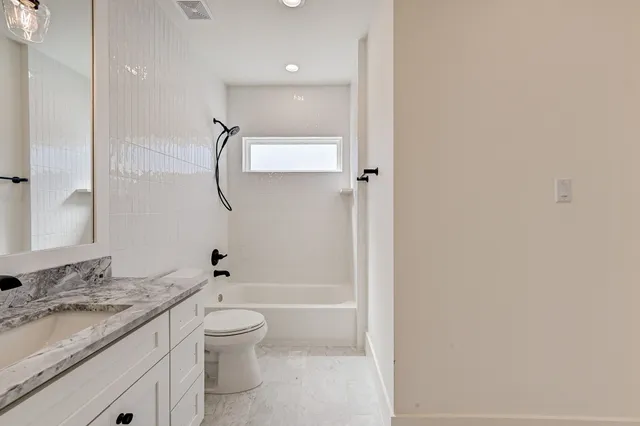 a bathroom with a granite countertop sink a toilet and shower