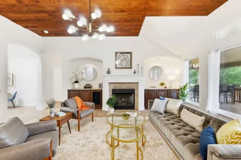 a living room with furniture a fireplace and a chandelier