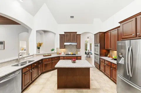 a kitchen with stainless steel appliances granite countertop a refrigerator stove and sink
