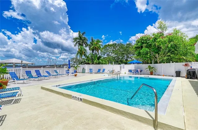 a swimming pool with barbeque oven table and chairs