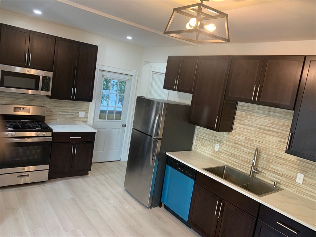 a kitchen with stainless steel appliances wooden cabinets a refrigerator and a stove top oven