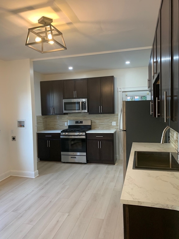 9 Kerwin Street, Unit 2 Boston, MA 02124 - Photo 2 of 13 a kitchen with stainless steel appliances wooden cabinets a sink and a stove