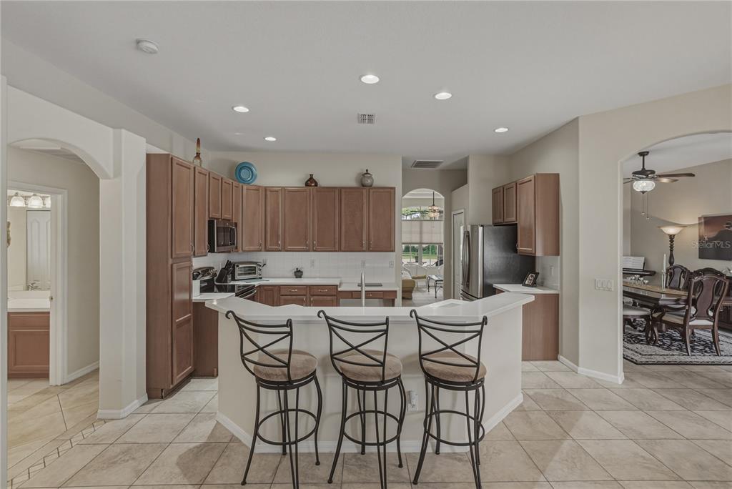 1542 Swamp Rose Lane Trinity, FL 34655 - Photo 9 of 64 a kitchen with a dining table chairs refrigerator and cabinets