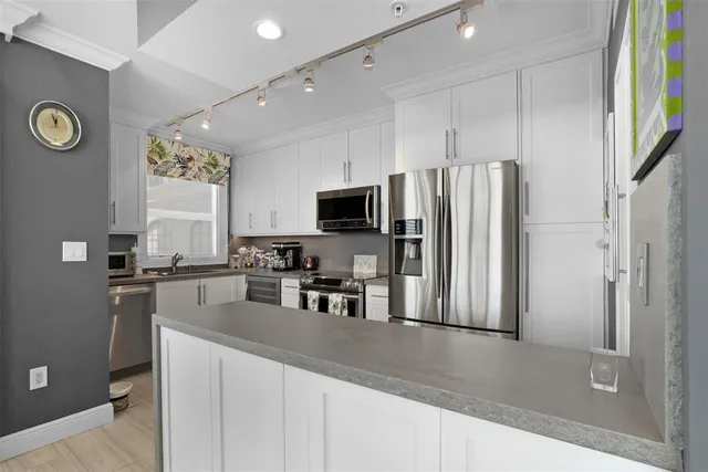 a kitchen with stainless steel appliances granite countertop a refrigerator a stove top oven a sink and dishwasher