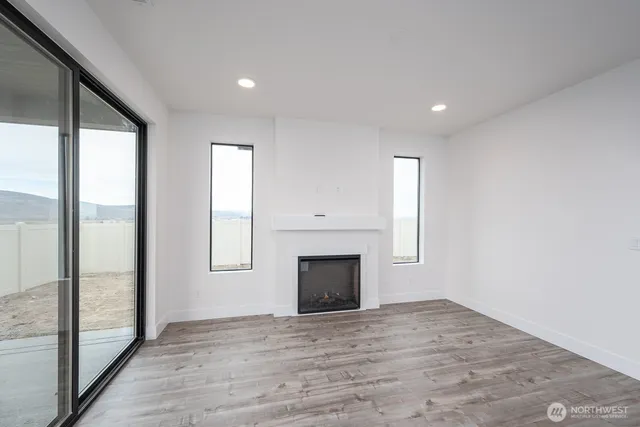 an empty room with windows and fireplace
