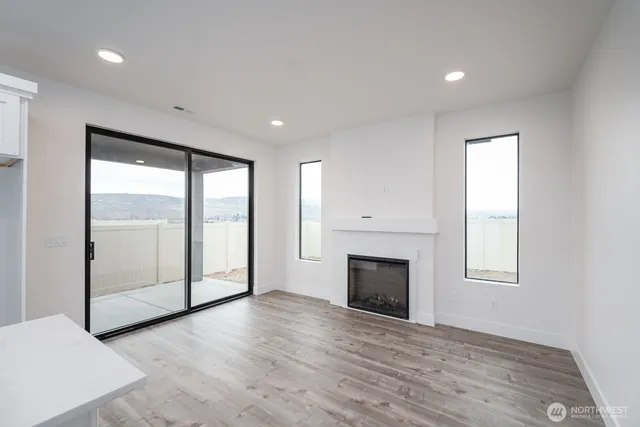 an empty room with wooden floor fireplace and windows
