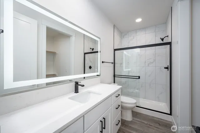 a bathroom with a shower sink vanity mirror and toilet