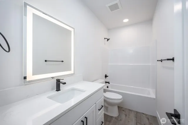 a bathroom with a granite countertop toilet a sink and a mirror