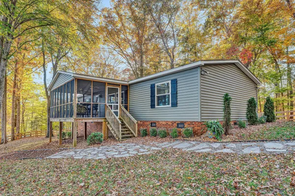 a view of a house with a yard and large trees