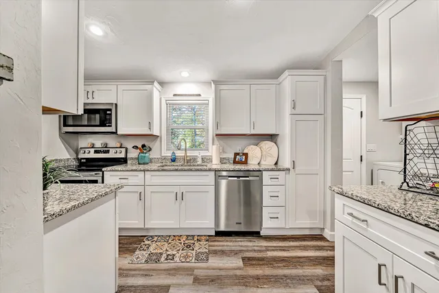 a kitchen with stainless steel appliances granite countertop a stove a sink and a refrigerator