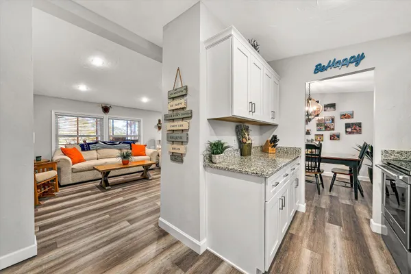 a living room with stainless steel appliances furniture wooden floor and a rug