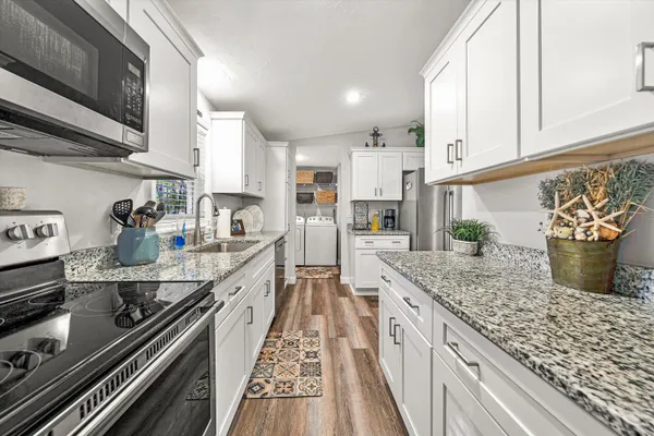 a kitchen with stainless steel appliances granite countertop a lot of counter space and wooden floor