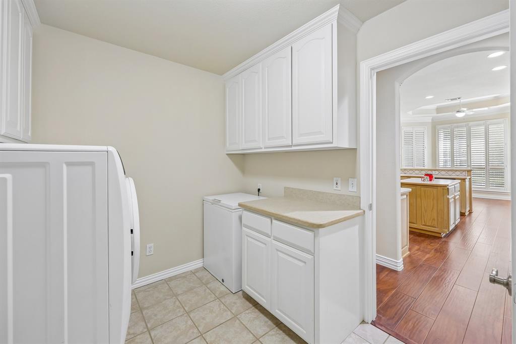 5409 Wedgefield Road Granbury, TX 76049 - Photo 15 of 39 White cabinetry with light-toned countertops, tiled flooring, and an arched doorway