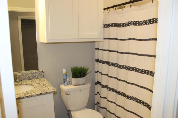a bathroom with a granite countertop sink and a toilet