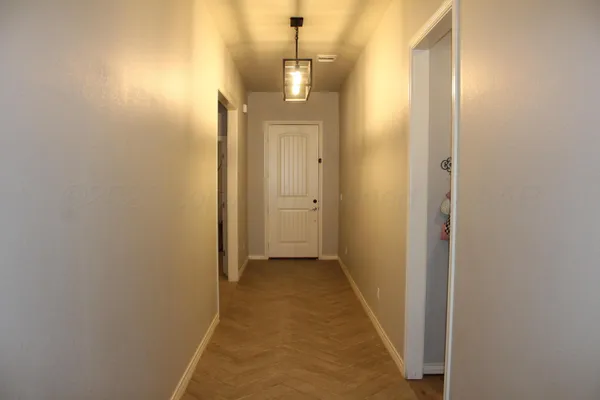a view of a hallway with wooden floor and a bathroom