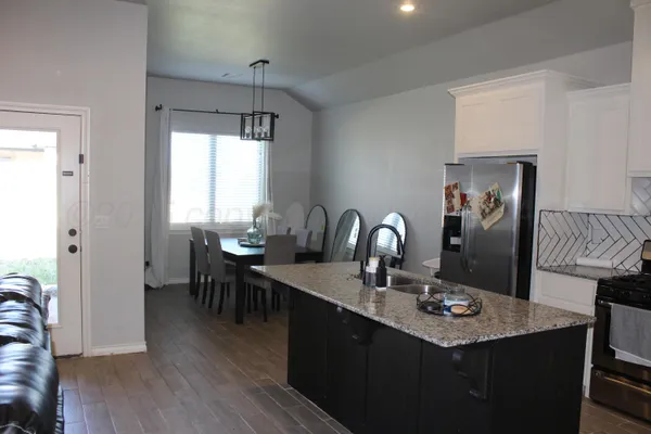 a dining room with wooden floor a chandelier a wooden table and chairs